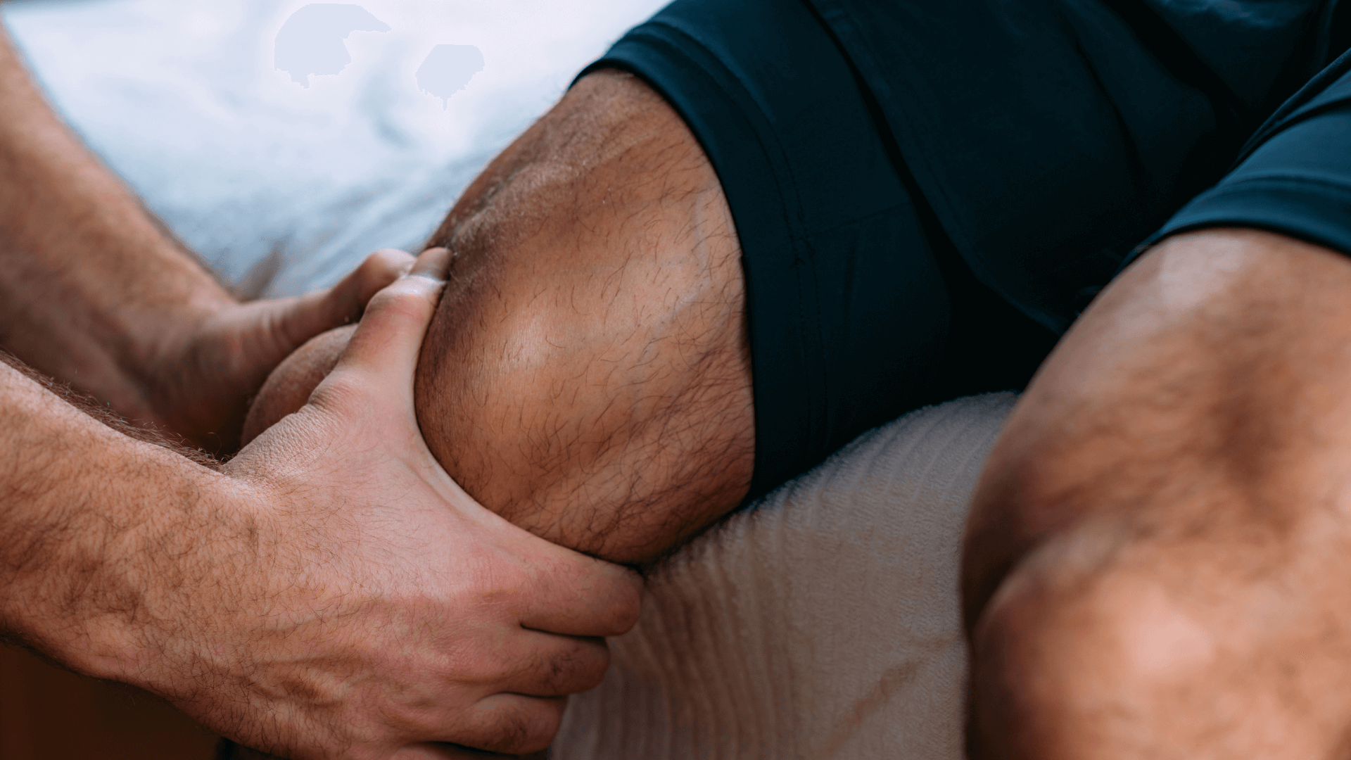 Manuelle Therapie Handgriff am Knie eines Patienten